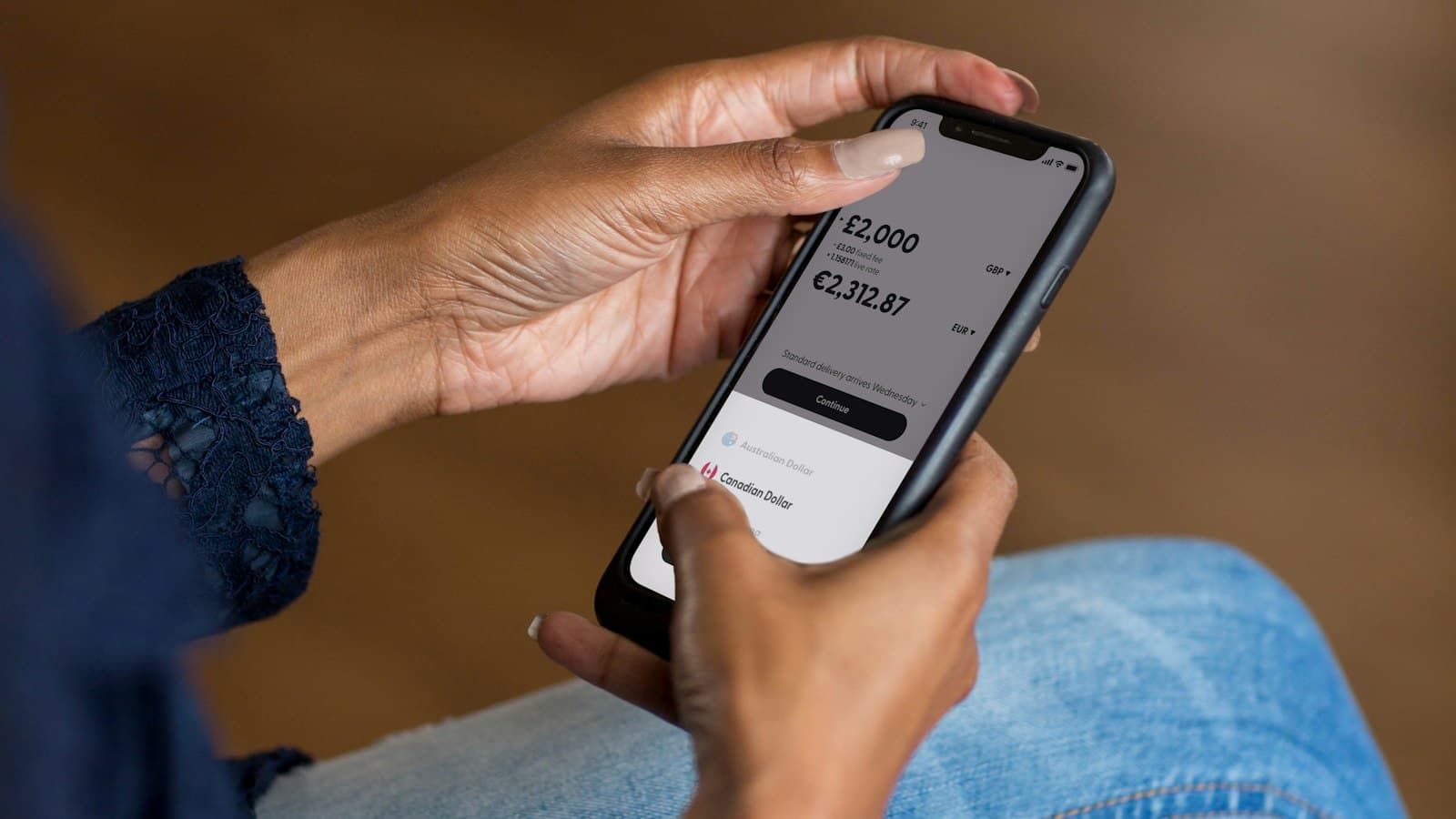 Two hands hold a smartphone showing an account balance in a banking app.